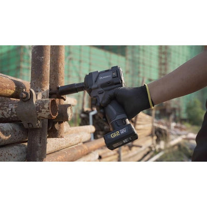 Person using a cordless impact driver on metal pipes with a blurred background